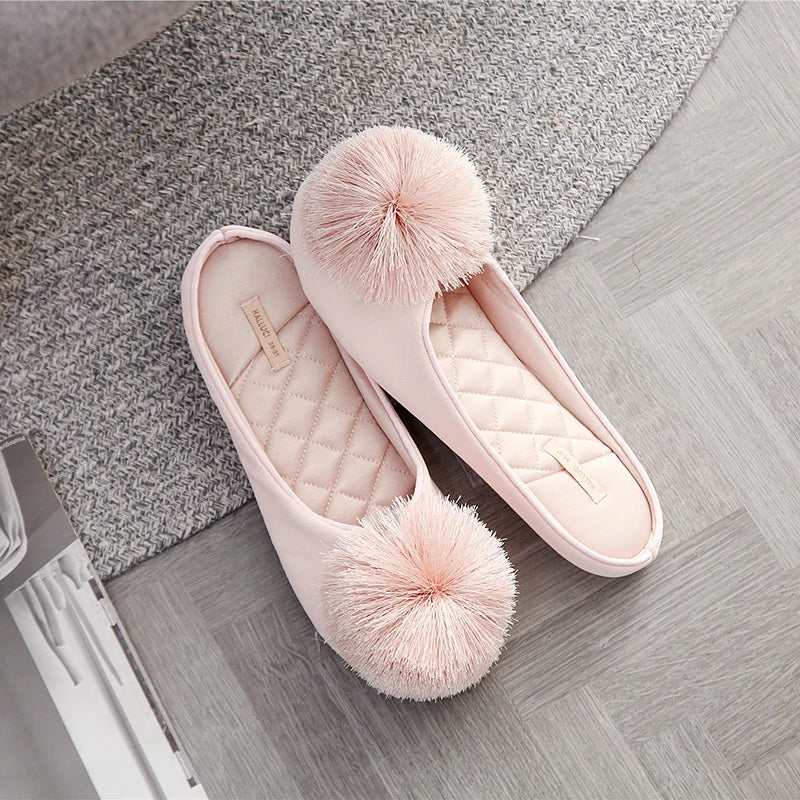 a pair of pink slippers with a pom - pom