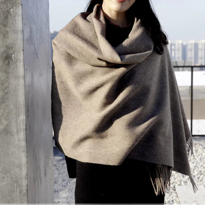 a woman wearing a gray shawl with a city in the background