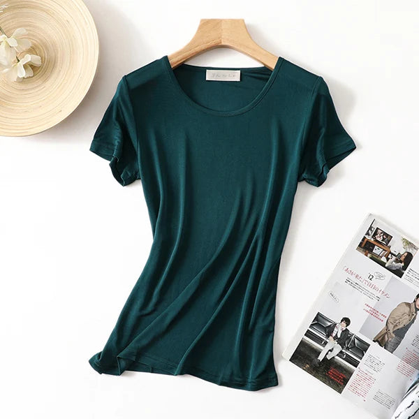 a green t - shirt next to a magazine and a hat