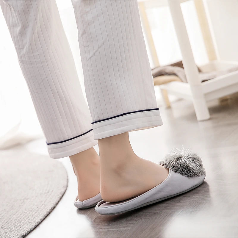 a woman's feet in slippers with a pom - pom on