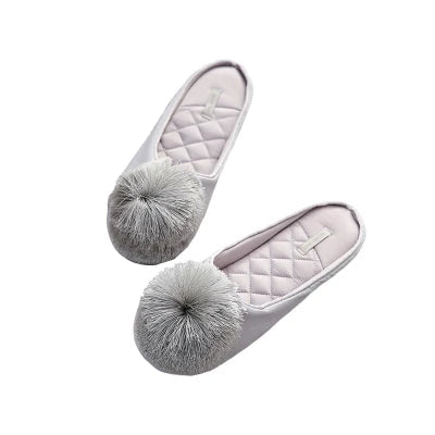 a pair of white slippers with a silver pom - pom