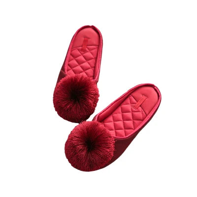 a pair of red slippers with a pom - pom