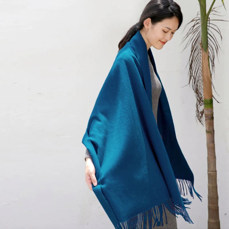 a woman wearing a blue shawl standing next to a tree