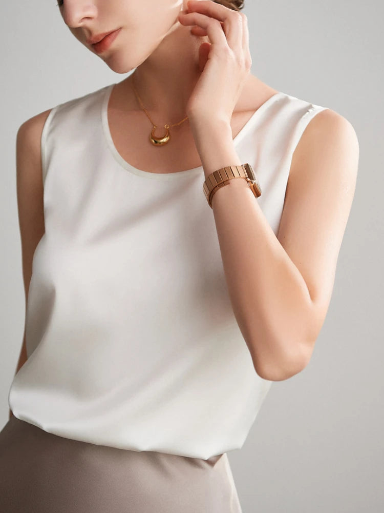 a woman wearing a white top and a gold bracelet