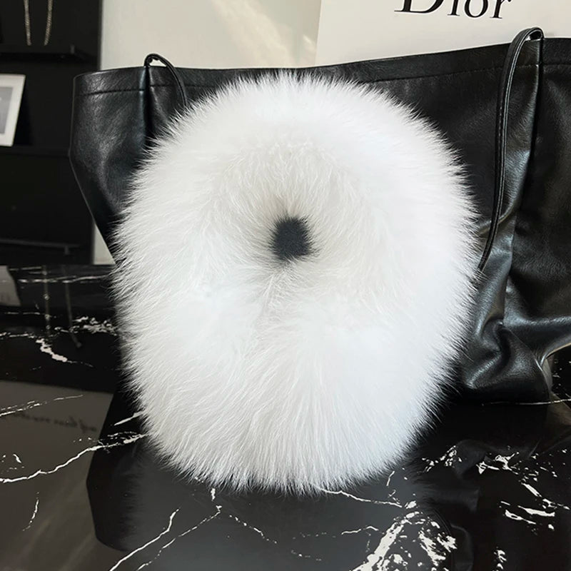 a black bag with a white fur ball on top of it