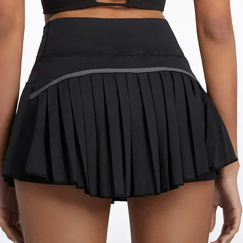 Back view of a woman wearing a black high waist pleated tennis skort, showcasing the skirt's layered design.