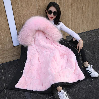 a woman sitting on the ground wearing a pink fur coat