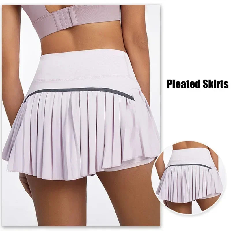 Back view of a woman modeling a light pink pleated tennis skort with a sporty fit, showing a small pocket detail.