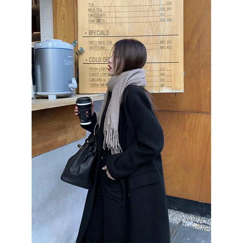 a woman standing in front of a sign holding a cup of coffee