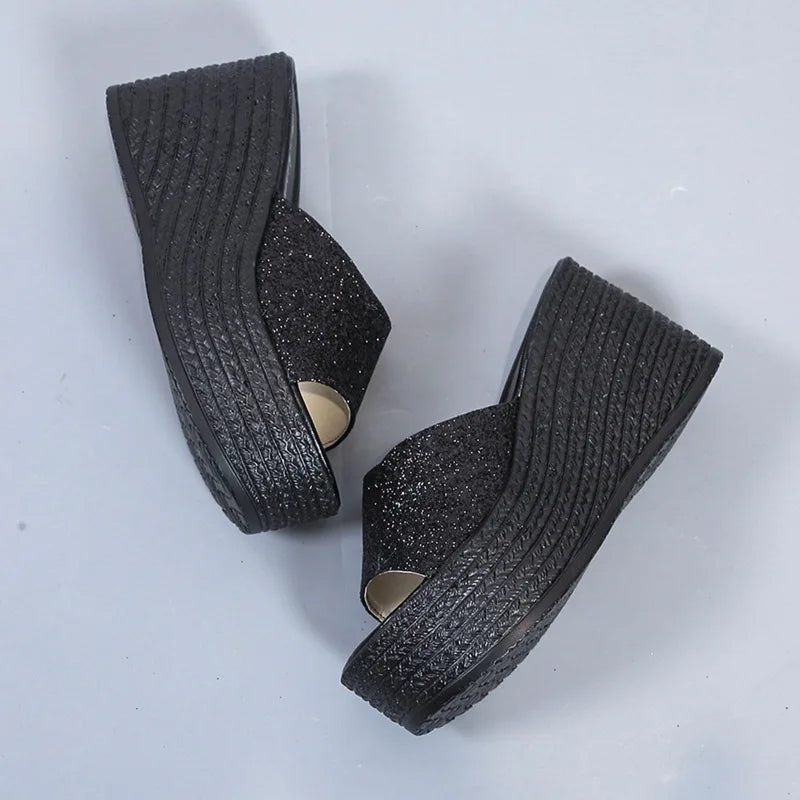 a pair of black wedges on a white surface