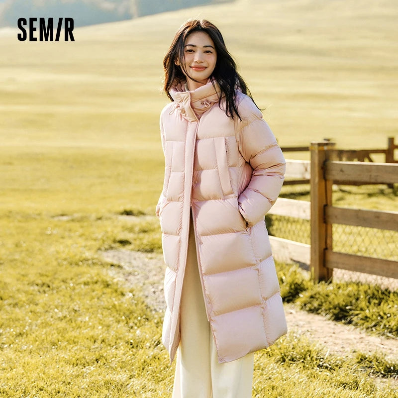 a woman standing in a field wearing a pink coat