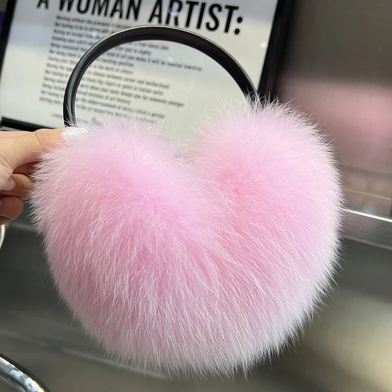 a person is holding a pink furry ear muffs