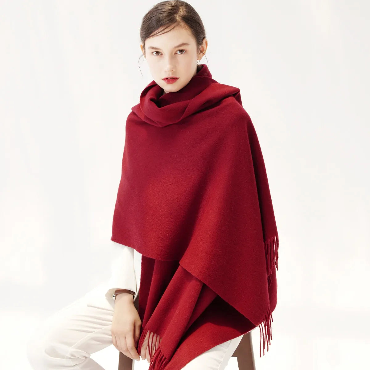 a woman sitting on a chair wearing a red shawl