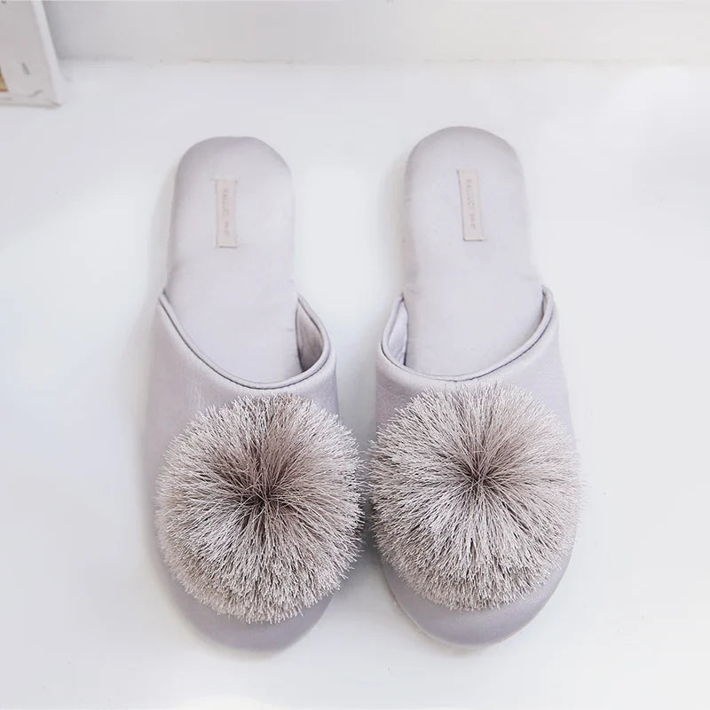 a pair of slippers with a pom - pom on top