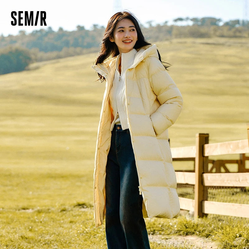 a woman standing in a field wearing a long coat