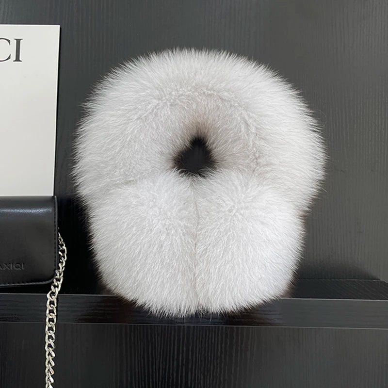 a white fur ball sitting on top of a black shelf