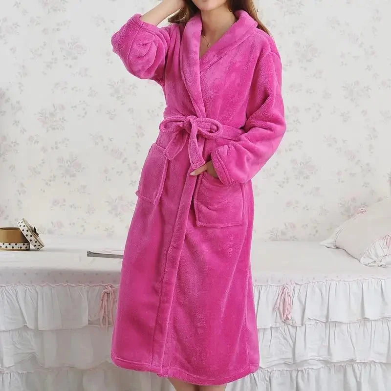 a woman in a pink robe standing in front of a bed