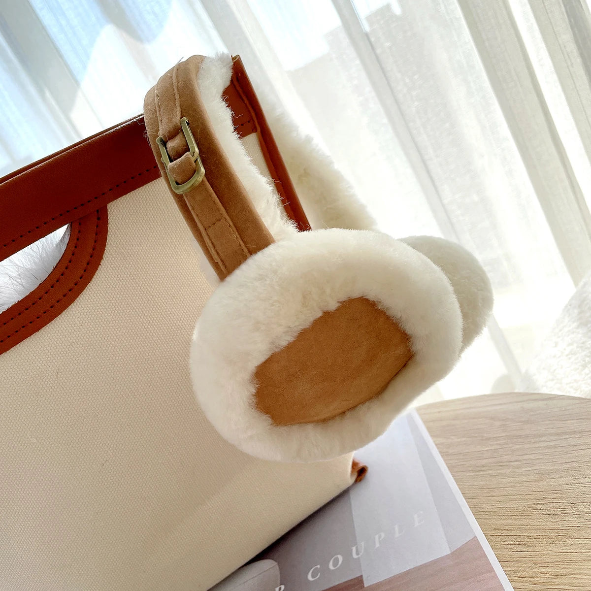 a white purse with a brown handle sitting on top of a book