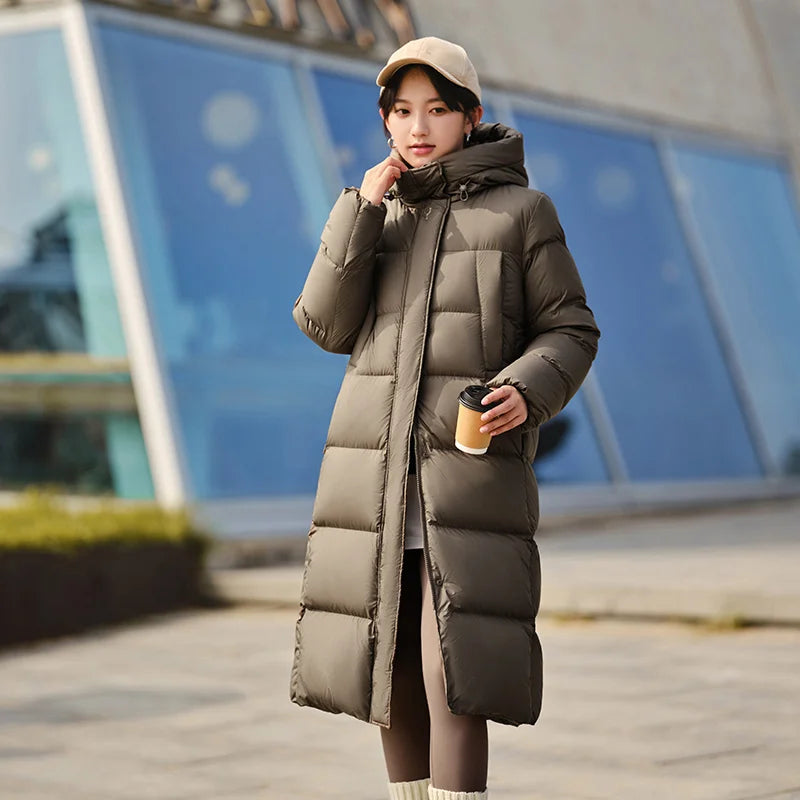 a woman in a long coat and hat talking on a cell phone