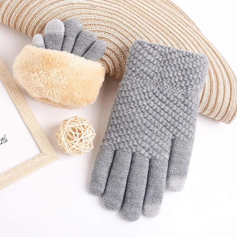 a pair of gray knitted gloves next to a picture frame