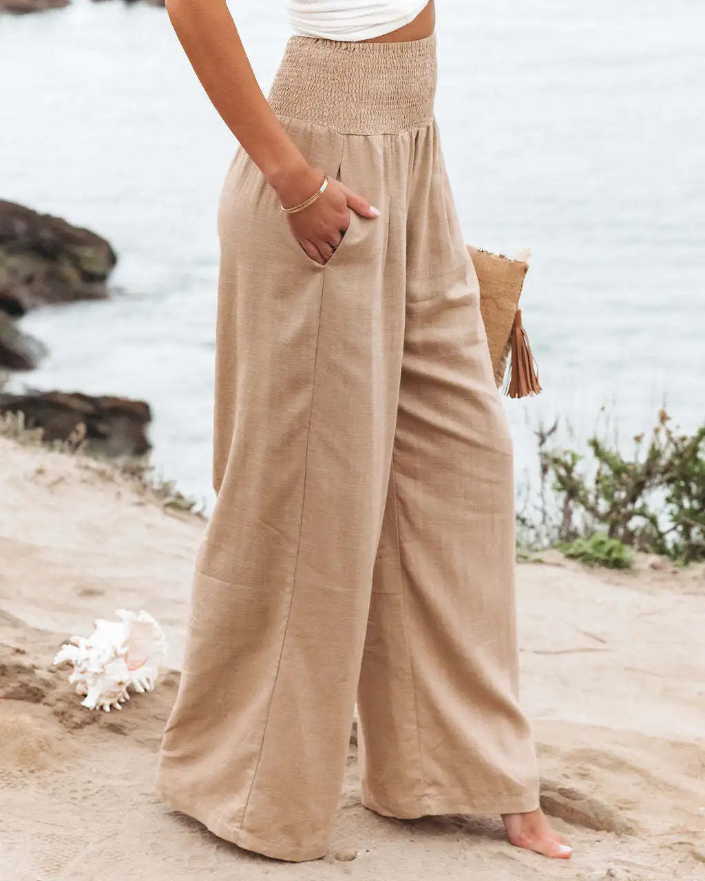 a woman standing on a beach with her hands in her pockets