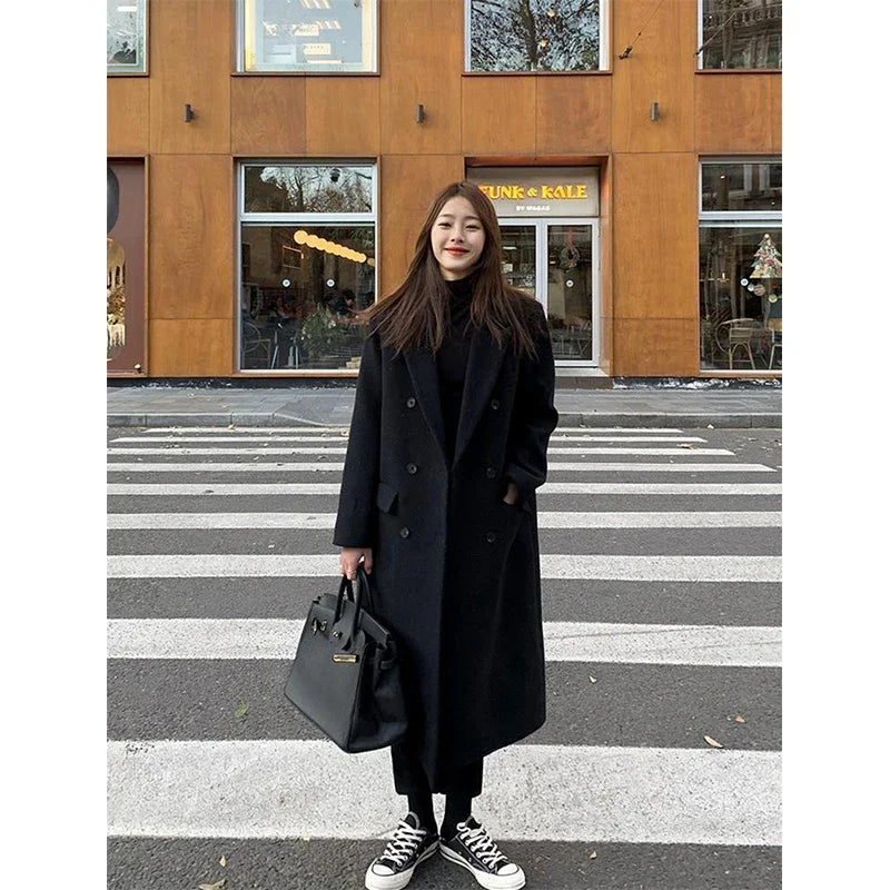 a woman standing in front of a building holding a black bag