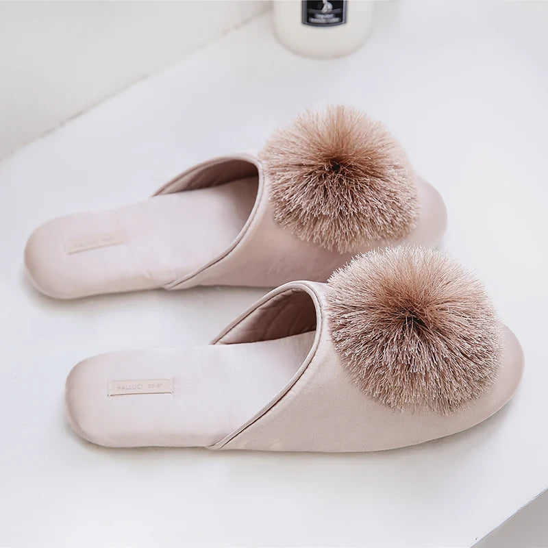 a pair of slippers with a pom - pom on top