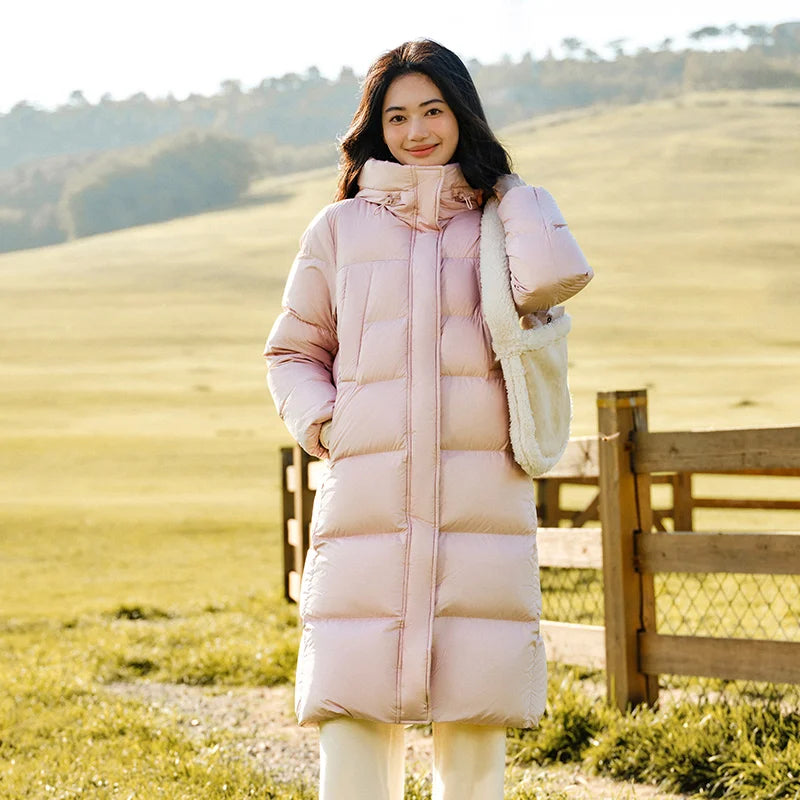 a woman in a long pink coat standing in front of a fence