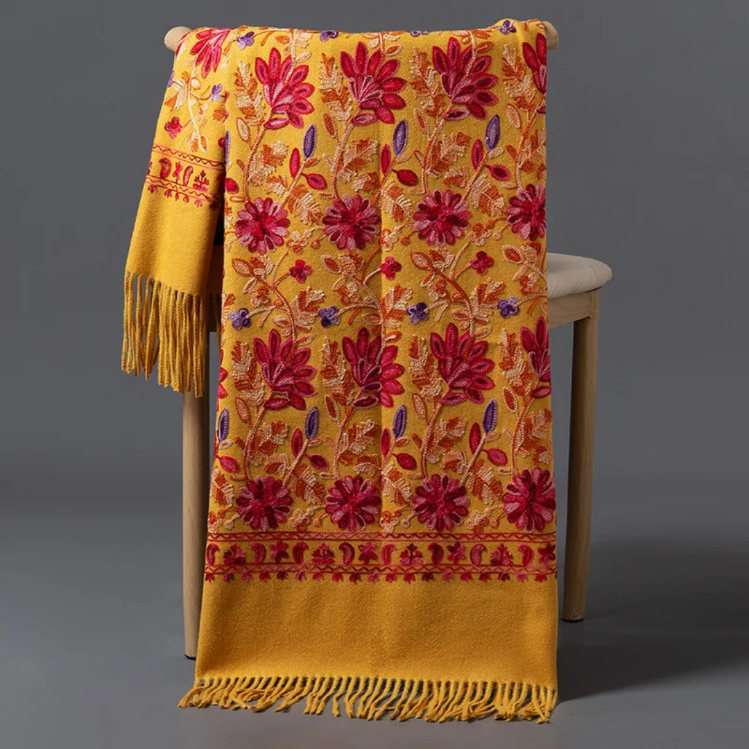 a yellow and red blanket sitting on top of a wooden chair