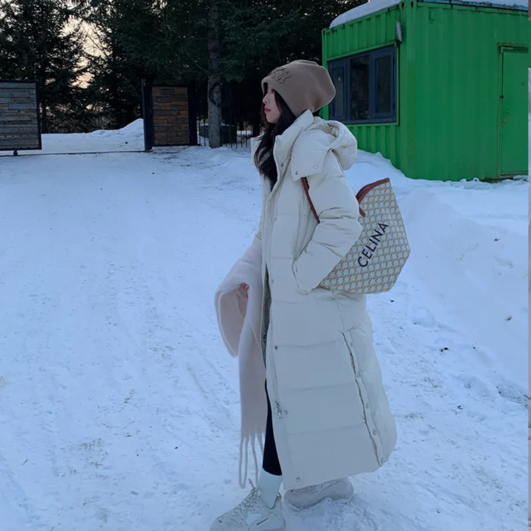 a woman standing in the snow holding a bag