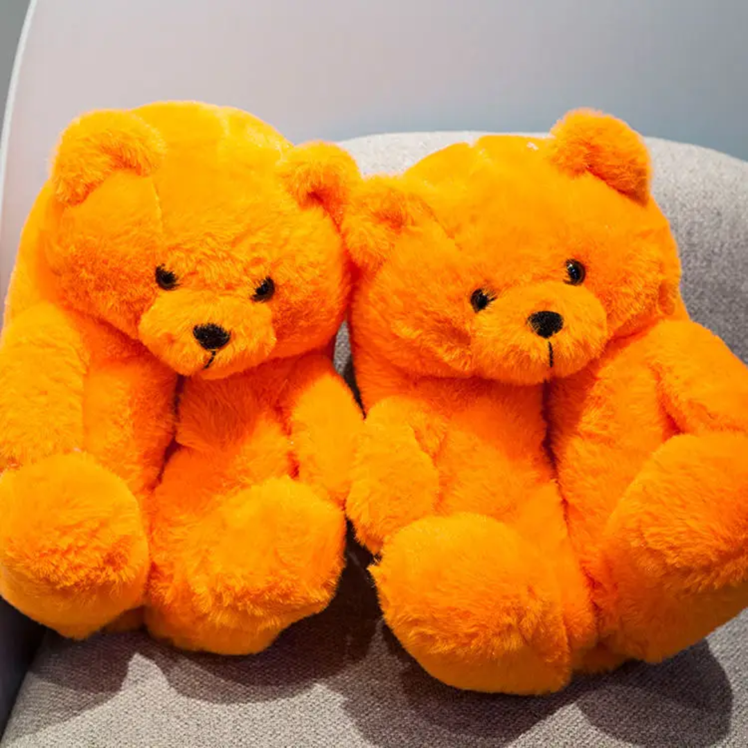 two orange teddy bears sitting on a gray chair