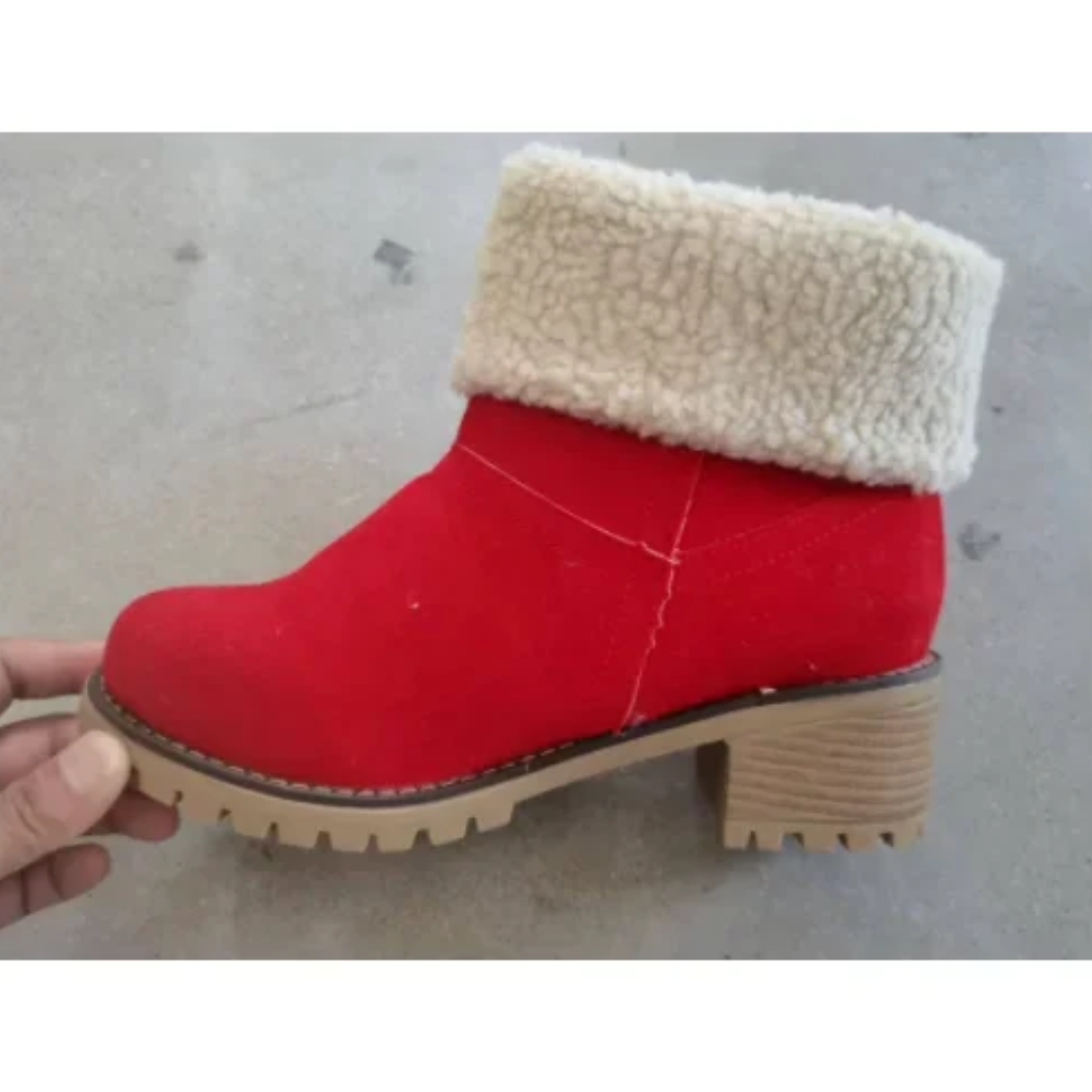 a hand is holding a pair of red boots