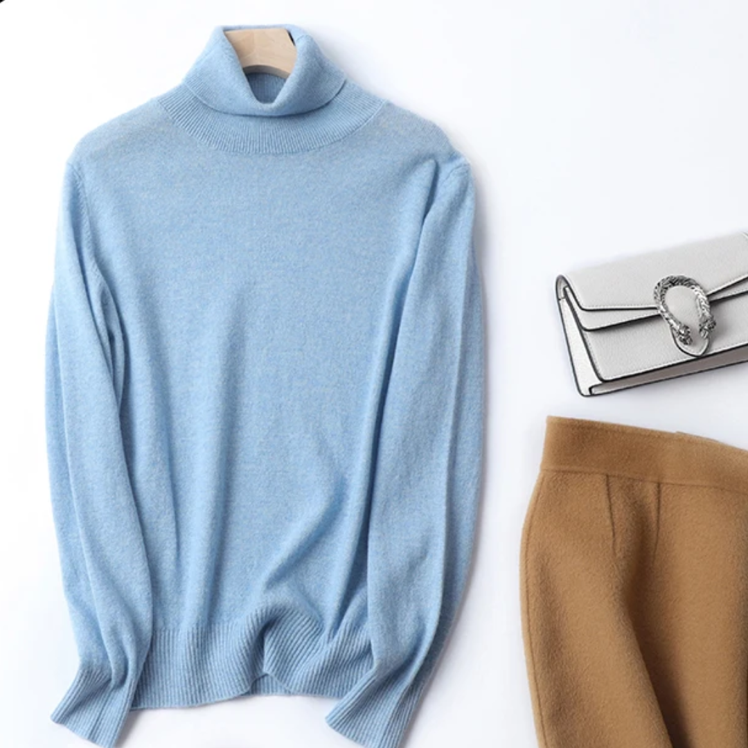 a blue turtle neck sweater next to a purse