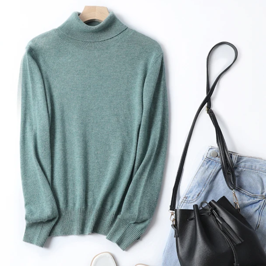 a pair of jeans and a green sweater are next to a purse